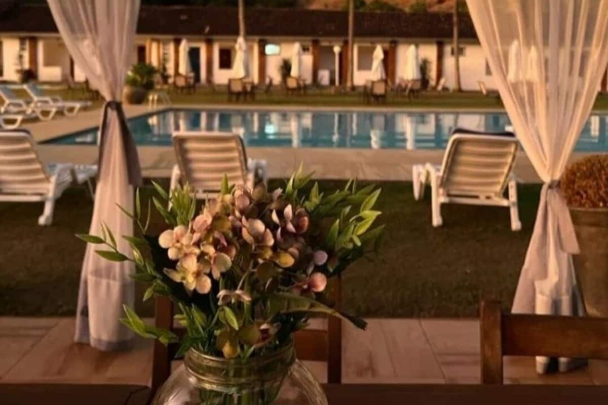 A poolside area with a clear view of the pool, lounge chairs, and a decorative vase with flowers.