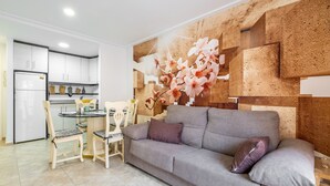 Una sala de estar con sofá, sillas, una mesa de comedor y una cocina al fondo.
