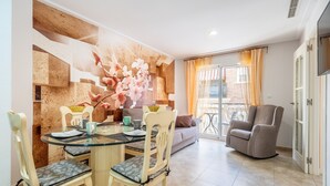 Un comedor con mesa de vidrio, sillas y un muro decorativo.