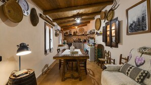 Un intérieur rustique avec une table à manger en bois, des chaises, un canapé et un coin cuisine.