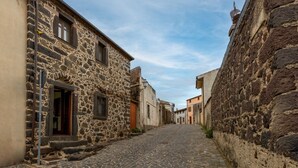 Une ruelle étroite pavée, bordée d’immeubles en pierre dont les fenêtres et les portes sont bien visibles.