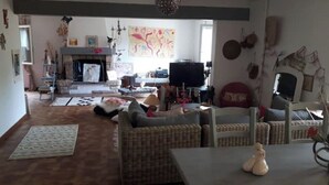 Una sala de estar con chimenea, muebles de mimbre y televisor.