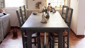 Un comedor con una mesa rectangular, seis sillas y diversas decoraciones en la pared.