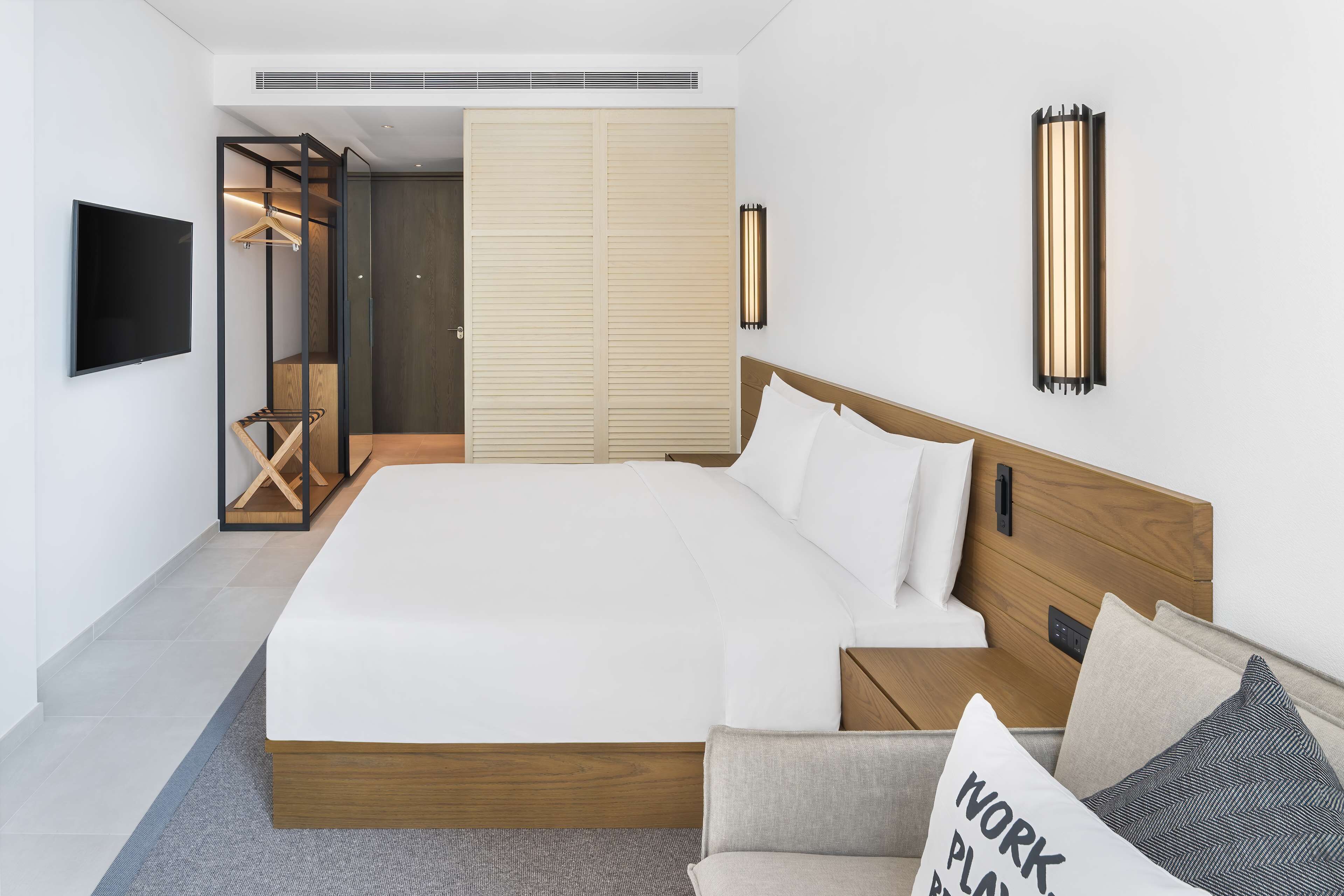 Un dormitorio moderno con una cama grande, un televisor, un armario y vestidor.