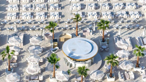 A beach resort with rows of sun loungers and palm trees, a pool area, and a clear view of the ocean. - Radisson Beach Resort Palm Jumeirah (Dubai)