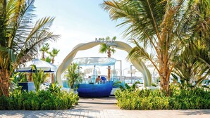 A resort entrance with a blue seating area, palm trees, and a clear sky. - Radisson Beach Resort Palm Jumeirah (Dubai)