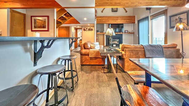 A cozy interior with a wooden ceiling, a fireplace, a dining area, and a seating area with a sofa and chairs.