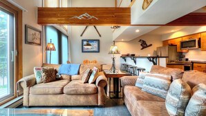 A spacious living area with two sofas, a dining table, and a kitchen in the background.