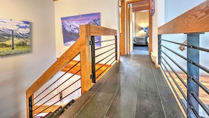 A staircase with wooden railings and a view of a bathroom in the background.