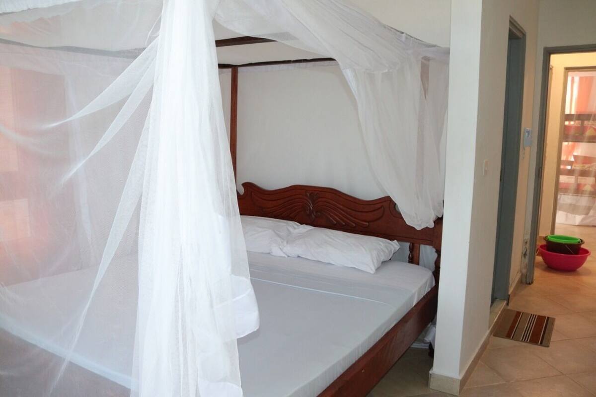 A single bed with a wooden headboard, white bedding, and a white canopy.