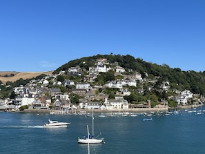 A coastal town with houses on a hillside, boats in the water, and a clear blue sky.