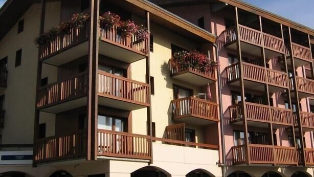 A multi-story building with balconies, arched windows, and a parking area. - 3rd floor, view mountain/village, balcony, parking, tv, 23m², Les Arcs (Bourg-Saint-Maurice)