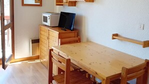 A dining area with a wooden table and chairs, a hanging light fixture, a microwave, and wooden cabinets. - 3rd floor, view mountain/village, balcony, parking, tv, 23m², Les Arcs (Bourg-Saint-Maurice)