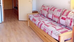 A cozy room with a wooden bed, a small wooden cabinet, and a door leading to another room. - 3rd floor, view mountain/village, balcony, parking, tv, 23m², Les Arcs (Bourg-Saint-Maurice)