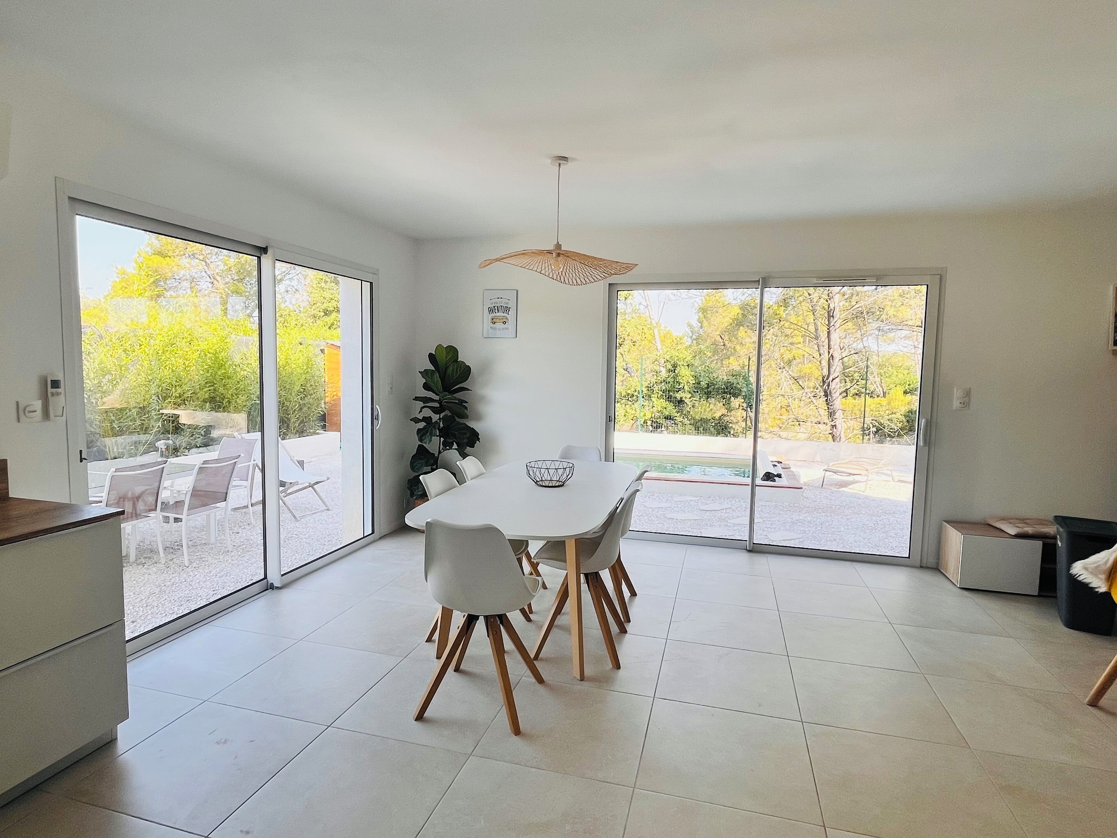 A modern kitchen with a dining area, large sliding glass doors leading to an outdoor patio with a pool.