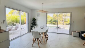 Een moderne keuken met een eethoek, grote schuifdeuren naar een buitenterras met een zwembad.