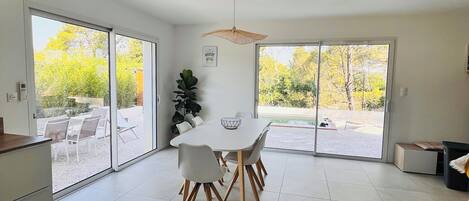 A modern kitchen with a dining area, large sliding glass doors leading to an outdoor patio with a pool.