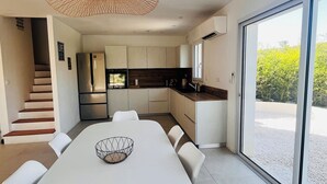Een moderne keuken met een grote eettafel, witte stoelen en een bijzondere hanglamp.