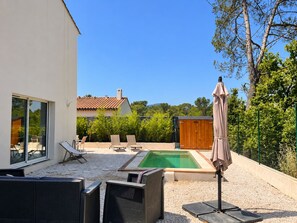 Un espace extérieur moderne doté d’une piscine, de chaises longues et d’une pergola.
