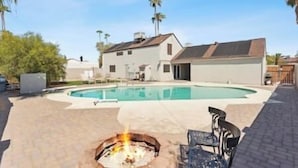 A swimming pool with a fire pit, a covered patio, and a house with a garage. - Luxury Vacation Home in Phoenix - Pool - Sleeps 17 (Phoenix)