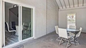 A covered outdoor area with a table and chairs, a sliding glass door, and a window. - Luxury Vacation Home in Phoenix - Pool - Sleeps 17 (Phoenix)