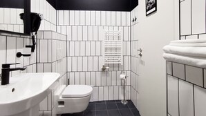 A compact bathroom with a white sink, toilet, and a towel rack. - Metropolis Budapest Boutique Hotel (Budapest)