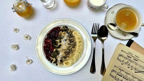 A breakfast setting with a plate of food, a glass of orange juice, a jug of milk, a cup of tea, and a music sheet. - Metropolis Budapest Boutique Hotel (Budapest)