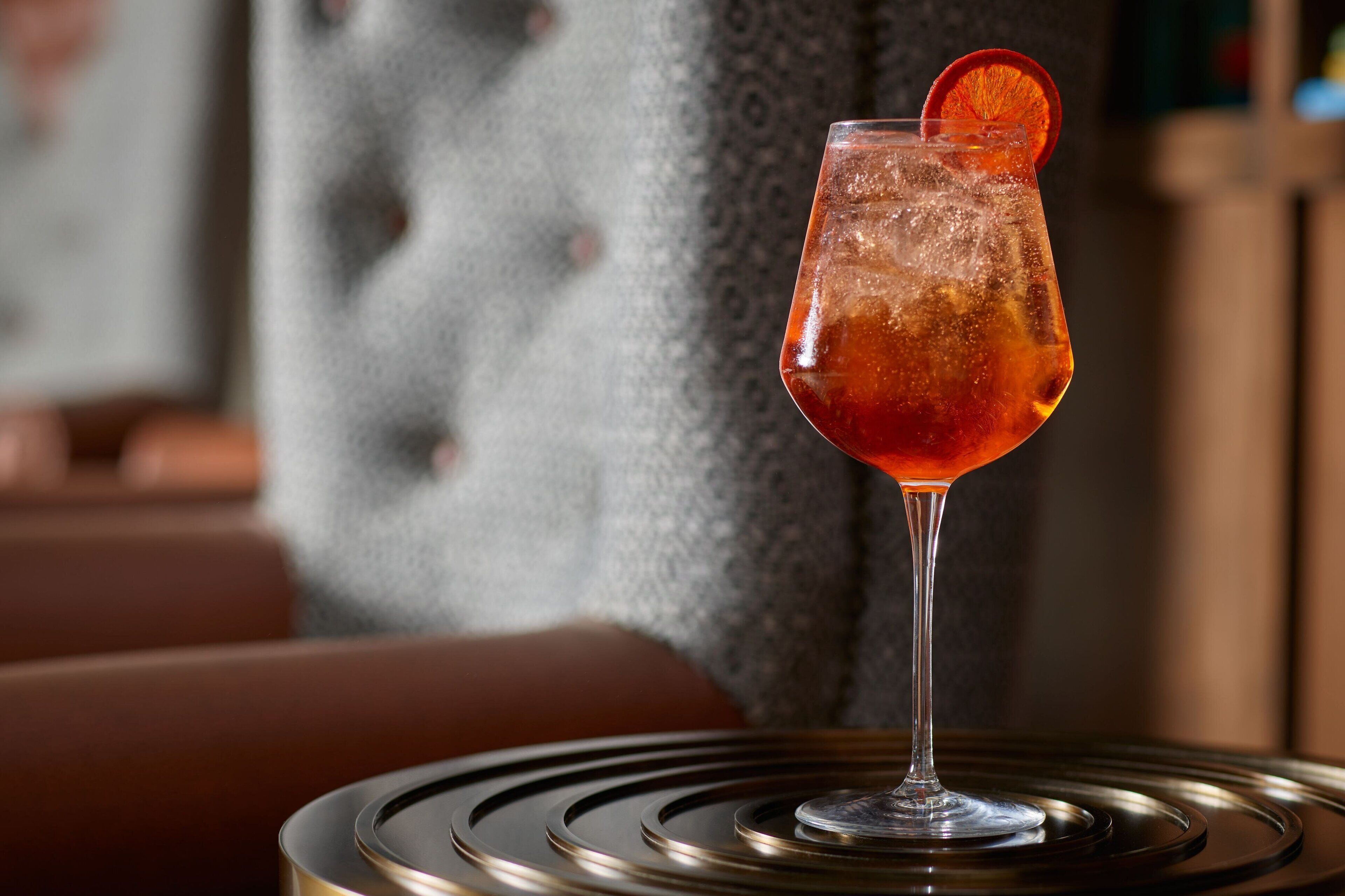 A cocktail glass with a slice garnish on a table.