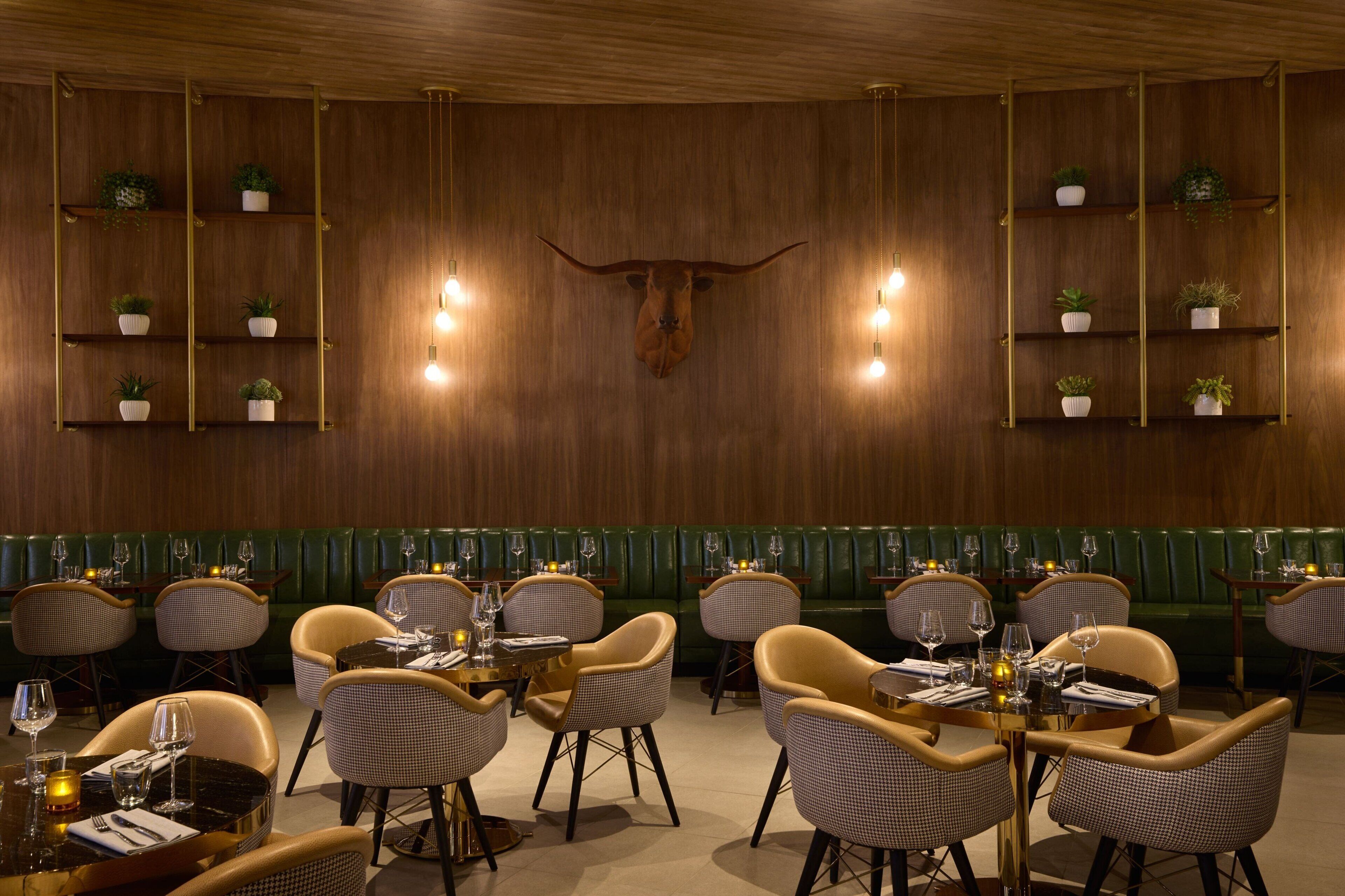 Ein Restaurant mit Holzwänden, grünen Sitzbänken und Korbstühlen.
