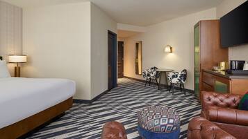 A hotel room with a bed, a desk, a chair, and a sofa.