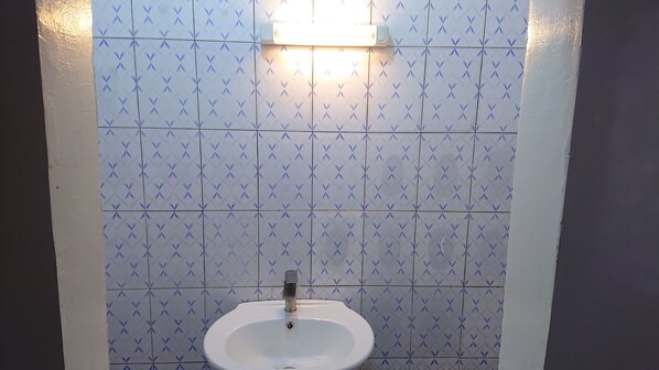 A bathroom with a white sink and blue patterned tiles. - CASE A MAMY (Nianing)