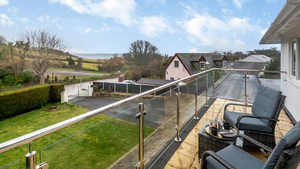 A balcony with a glass barrier, outdoor furniture, and a view of a rural landscape. - Broadsands (Paignton)