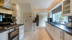 A modern kitchen with stainless steel appliances, white cabinetry, and a long countertop. - Broadsands (Paignton)