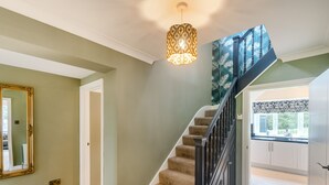 A staircase with a black railing, a light fixture above, and a view into a kitchen area. - Broadsands (Paignton)