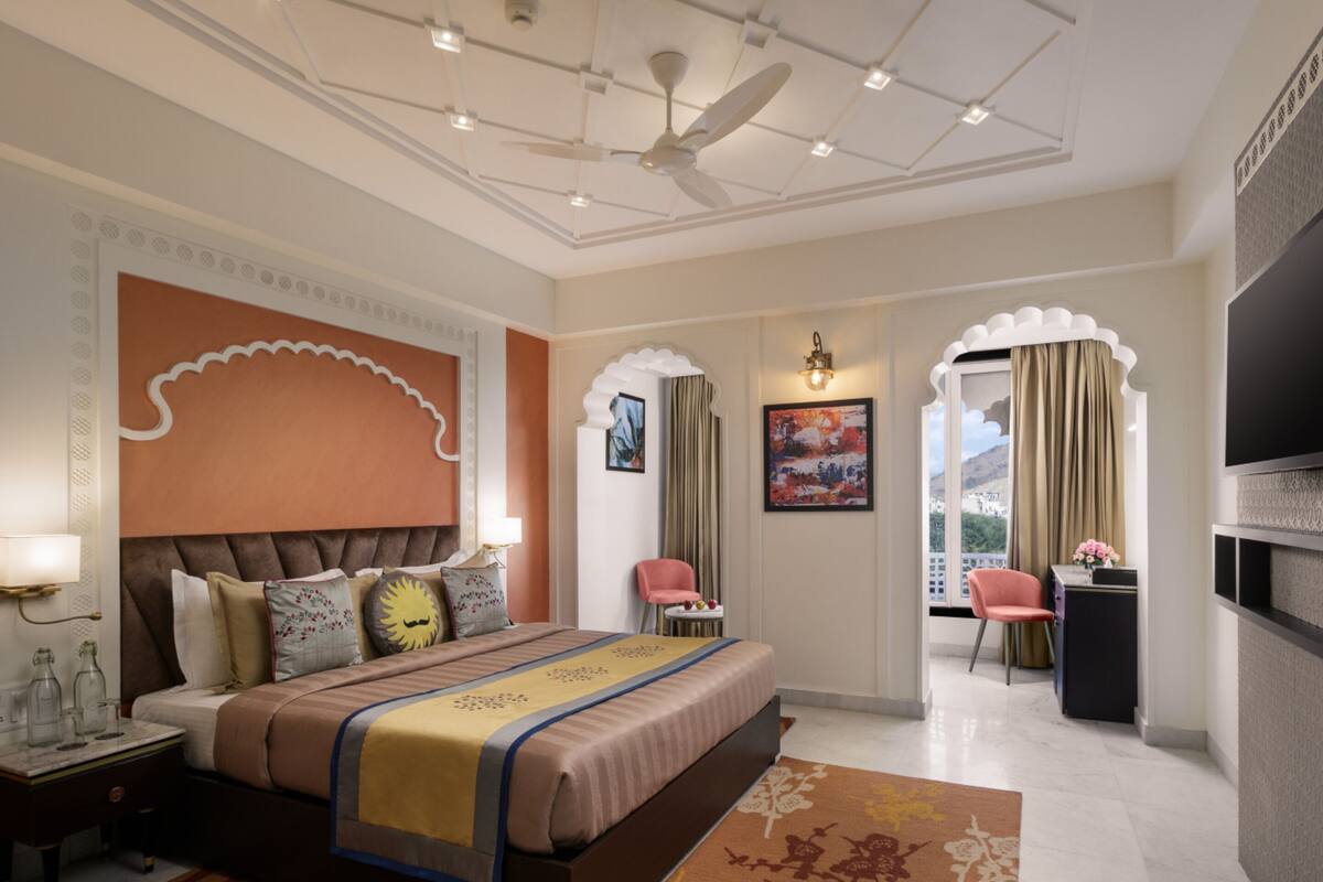 A modern hotel room with a large bed, a desk, and a TV.