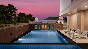A pool area with a view of a traditional building and a mountain in the background. - juSTa Ssatva Resort - Udaipur (Udaipur)