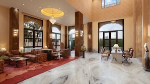 A spacious lobby with a marble floor, comfortable seating, and large windows offering views of the outdoors. - juSTa Ssatva Resort - Udaipur (Udaipur)