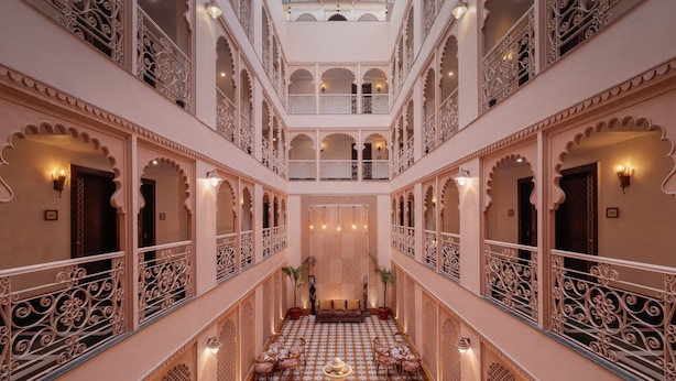 A multi-level interior with ornate railings, a central seating area with tables and chairs, and a patterned floor. - juSTa Ssatva Resort - Udaipur (Udaipur)