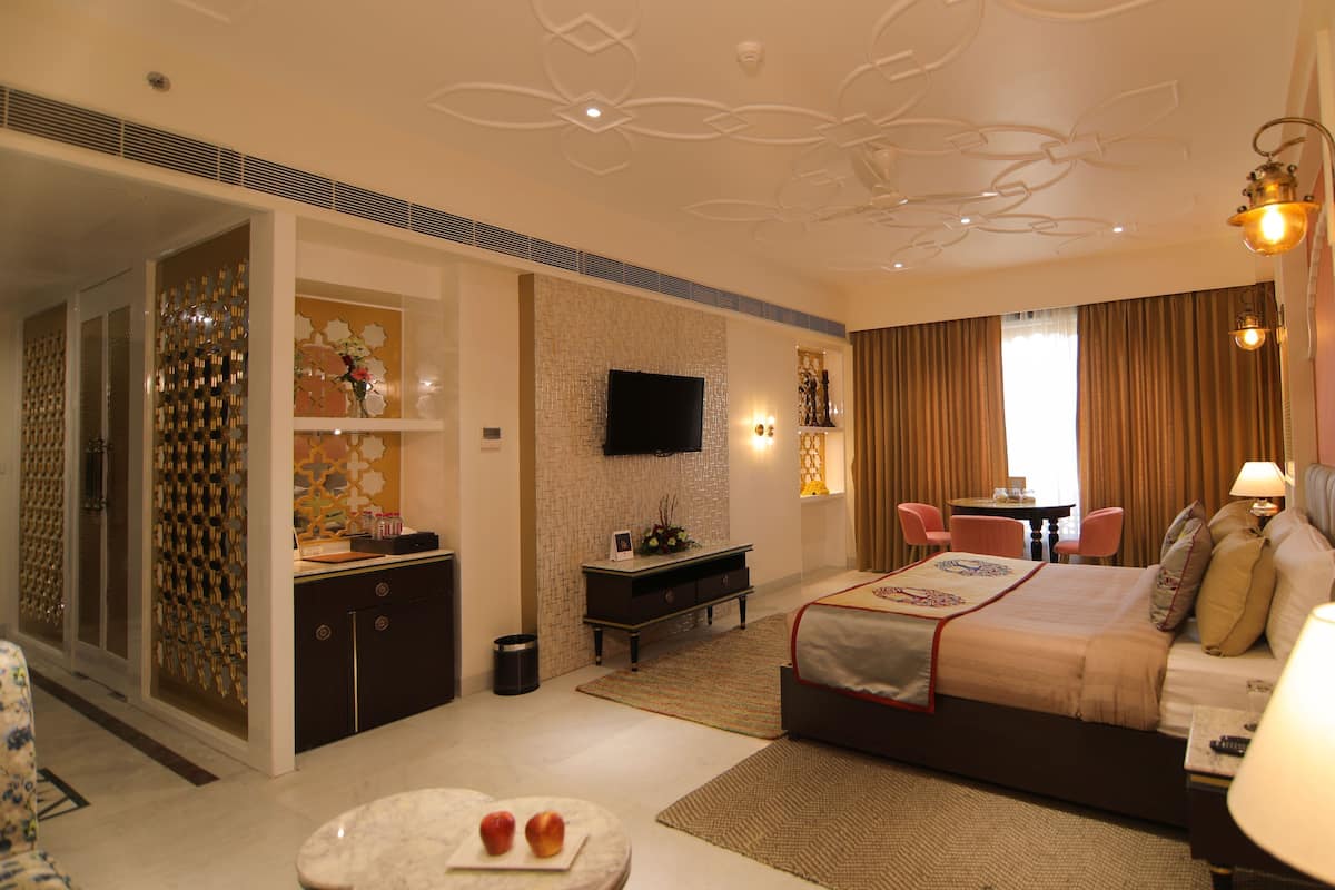A hotel room with a bed, a TV, a desk, and a dining area.