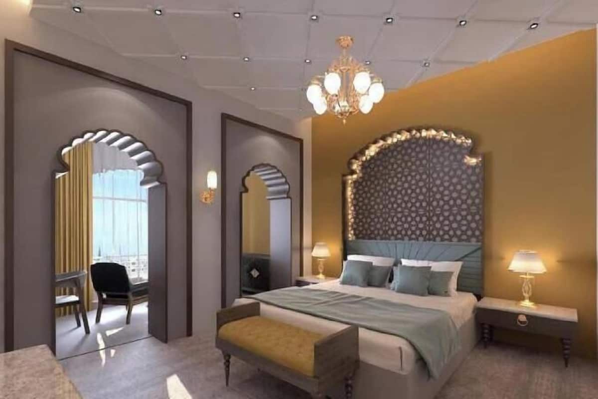 A modern hotel room with a large bed, a desk, and a chair.