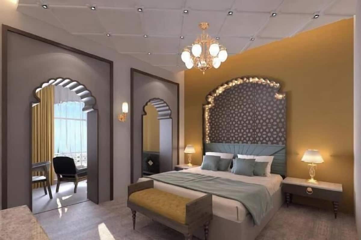 A modern hotel room with a large bed, a desk, and a chair.