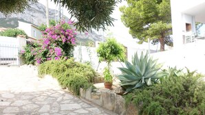 A stone-paved courtyard with a variety of plants, including a large agave and bougainvillea flowers, and a potted plant. - Cosy villa with private pool and sea and mountain views, in Denia (Denia)