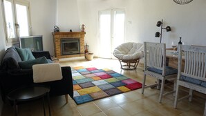 A cozy living room with a fireplace, a colorful rug, a sofa, a dining table with chairs, and a television. - Cosy villa with private pool and sea and mountain views, in Denia (Denia)