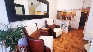 A hotel lobby with a wooden floor, two leather armchairs, a large mirror, and a potted plant. - Frutas do Mar apartamento (Portimão)
