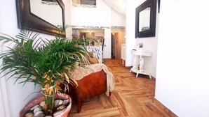 A hallway with a large potted plant, a vintage sofa, and a white console table. - Frutas do Mar apartamento (Portimão)