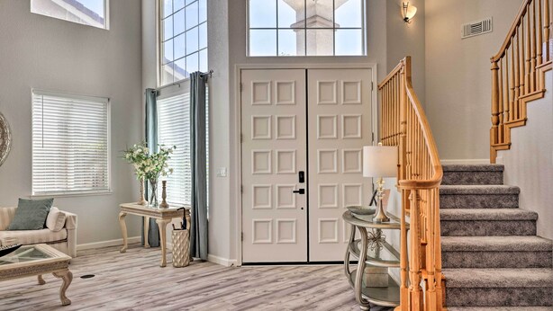 A spacious living room with a large window, a staircase, and a door with a modern design. - Family-Friendly Modesto Home w/ Grill & Yard (Modesto)