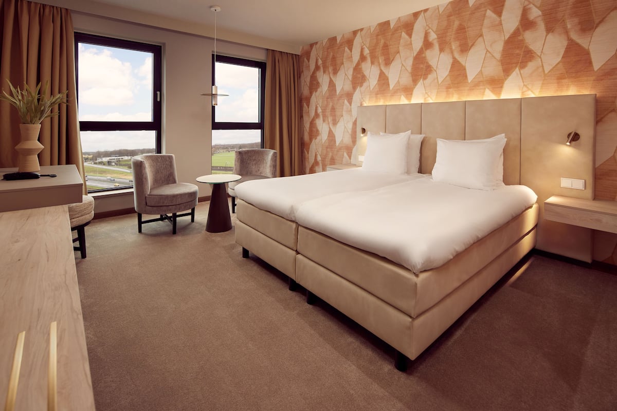 Ein modernes Hotelzimmer mit einem großen Bett, einem Schreibtisch, einem Stuhl und einem kleinen Tisch.