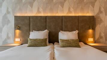 A double bed with two pillows, a headboard with integrated lighting, and a patterned wall in the background.