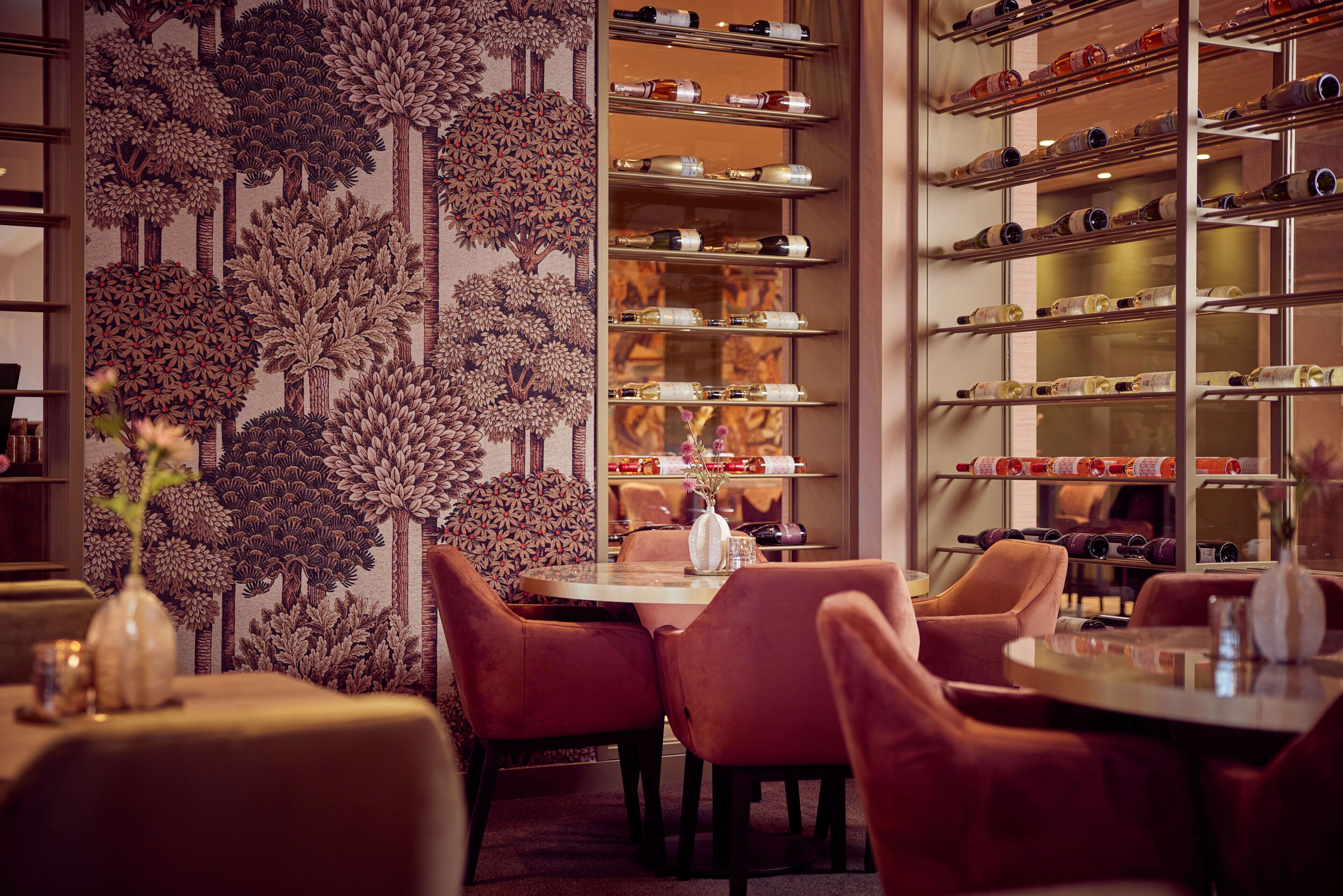 A restaurant with a wall mural, a wine rack, and a dining area with chairs and a table.