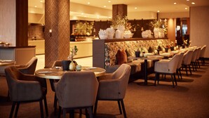 Ein modernes Restaurant mit runden Tischen, gepolsterten Stühlen, einer dekorativen Wand und stimmungsvoller Beleuchtung.
